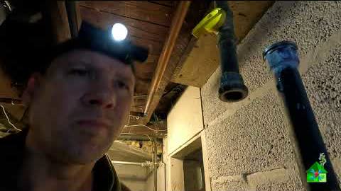 Dave under a basement floor with a headlamp on, next to a new water tank vent pipe