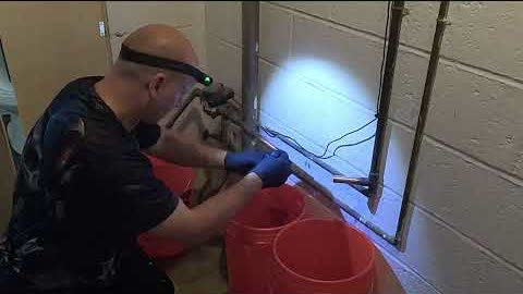 Dave with a headlamp, drilling into a basement block wall
