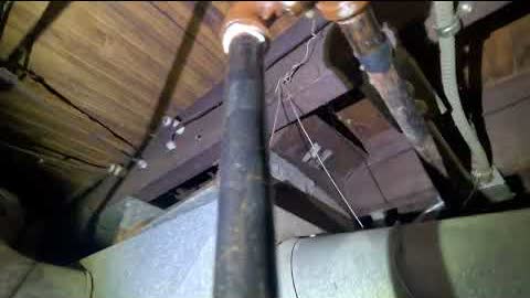 Gas and water lines under basement joists, lit by a work light