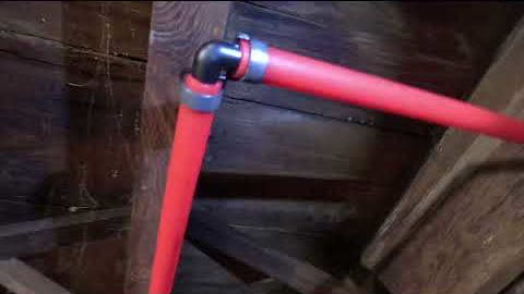 A new red PEX supply line run through basement joists