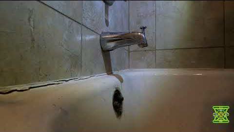 A cracked bathtub with a worn spout, filmed during an estimate